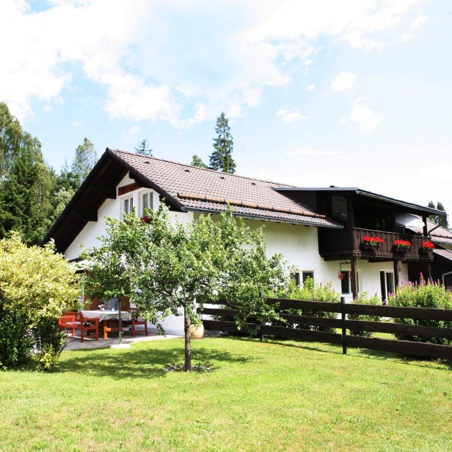 Gemütliche Terrasse am Ferienhaus Wernerhäusl mit Blick ins Grüne Ferienhaus Wernerhäusl in Zwiesel mit großzügiger Terrasse und Gästen beim gemütlichen Essen im Grünen